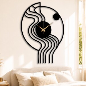 May include: A black metal wall clock with an abstract design. The clock has a circular face with gold hands, set against a black backdrop. The design incorporates wavy lines and a circular shape, creating a modern aesthetic. The clock is mounted on a white wall.