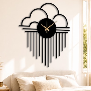 May include: A black, modern wall clock with a cloud-like design. The clock face is round with gold-colored hands. Vertical lines extend downward from the clock, creating a rain-like effect. The clock is mounted on a white wall above a bed.