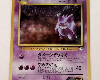 以下が含まれることがあります： レベル39、HP80のナツメのゲンガーが描かれた紫色のポケモンカード。カードには、暗い星空を背景にしたゴーストタイプのポケモンのイラストと、日本語のテキスト、そしてカード全体を囲む金色の枠がデザインされています。