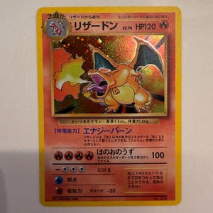 Könnte beinhalten: Eine japanische holografische Charizard-Sammelkarte, die das Feuer-Pokémon mit orangefarbenen Schuppen und Flügeln zeigt, mit 120 KP, Level 76 und einem goldenen Sternsymbol. Die Karte enthält japanischen Text sowie Feuer-Energiesymbole.