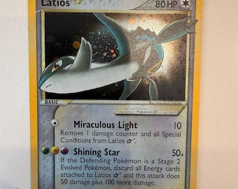 Può includere: Una carta collezionabile Pokémon Latios Star con 80 HP. La carta presenta un'illustrazione olografica della creatura Latios blu e bianca su uno sfondo scuro e stellato. Include gli attacchi Miraculous Light e Shining Star.