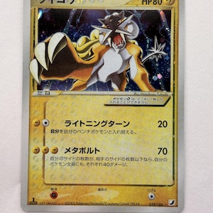 Op de afbeelding: Een Raikou Gold Star Pokemon-ruilkaart met het personage in een dynamische houding tegen een donkere, sterrenhemel-achtergrond. De kaart heeft een gele rand, 80 HP en Japanse tekst, inclusief de aanvallen Lightning Turn en Metabolt.