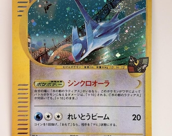 Può includere: Una carta collezionabile Pokémon giapponese raffigurante Latios della Città dell'Acqua. La carta presenta un bordo giallo, un'illustrazione olografica della creatura blu che vola sopra un ponte, 70 HP e testo giapponese che descrive le abilità.