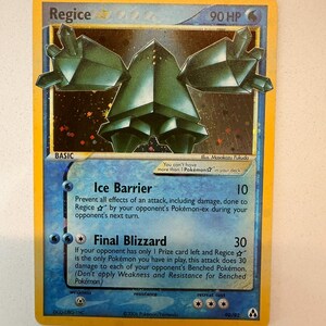 Puede incluir: Una carta coleccionable Regice Star con 90 HP, que muestra una ilustración de una criatura cristalina de color verde oscuro. La carta presenta los ataques Ice Barrier y Final Blizzard, con texto sobre las reglas, el ilustrador Masakazu Fukuda y el copyright de 2006.