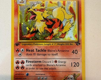 以下が含まれることがあります： 黄色い縁取りのホログラフィック仕様のブレイズ・ウィンディ（Blaine's Arcanine）トレーディングカード。炎タイプのポケモンのイラスト、Heat TackleとFirestormのテキストが記載され、身長190.5cm、体重155.1kgと表記されています。1進化ポケモンカードです。