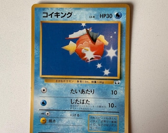 Può includere: Una carta collezionabile Pokémon Magikarp giapponese di livello 8 con 30 HP. La carta mostra un'illustrazione di un pesce arancione su sfondo blu, con il testo 'コイキング', 'たいあたり' e 'じたばた'. Il bordo è color oro.
