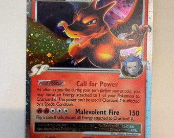 Può includere: Una carta collezionabile olografica Charizard LV.X che raffigura il Pokémon di tipo fuoco in una posa dinamica. La carta mostra 120 HP, il Poké-POWER Call for Power e l'attacco Malevolent Fire. Include un piccolo ritratto e del testo.