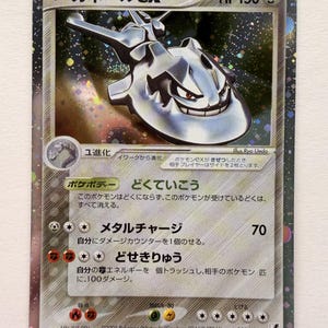 May include: A Steelix ex trading card featuring a metallic silver creature with a segmented body and sharp features. The card displays the text "ハガネールex" at the top, "HP 150", and various Japanese text descriptions, attack names, and energy symbols against a dark, starry, holographic background.
