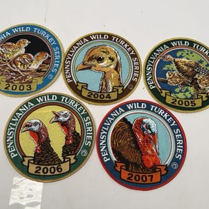 May include: Five circular embroidered patches from the Pennsylvania Wild Turkey Series, dated 2003 through 2007. Each patch features detailed imagery of wild turkeys in various life stages, surrounded by text and a gold-colored border.
