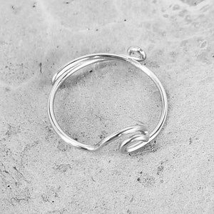 May include: A silver ring with a twisted wire design. The ring has a small loop at the top for attaching a charm.