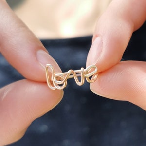 May include: A gold wire ring with the word "LOVE" spelled out in wire.