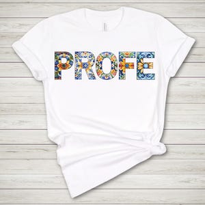 May include: White t-shirt with the word "PROFE" in large, colorful letters. The letters are filled with a floral pattern in shades of blue, yellow, and orange. The shirt is made of a soft material and has short sleeves.