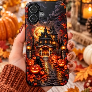 May include: A black smartphone case featuring a detailed Halloween-themed illustration of a dark, multi-story mansion at night under a full moon. The scene includes a stone path, glowing jack-o'-lanterns, a black cat, and autumn leaves.