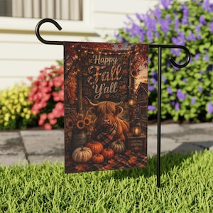 May include: A rectangular garden flag hanging on a black metal stand features a Highland cow wearing a plaid scarf, surrounded by pumpkins, sunflowers, and lanterns. The text Happy Fall Y'all is printed at the top against a rustic autumn backdrop.