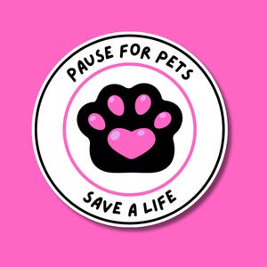 May include: A circular sticker with a white background and a thin pink border. In the center is a black animal paw print with pink pads, including a heart-shaped central pad. The text PAUSE FOR PETS is arched above and SAVE A LIFE below.