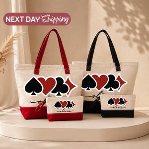 May include: Two canvas tote bags and two matching zippered pouches featuring a playing card suit design of spades, hearts, clubs, and diamonds. One set has red accents and handles, while the other has black accents and handles. The name Olivia is printed.