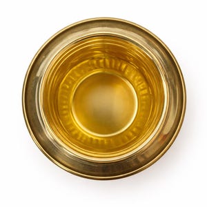 May include: Overhead view of a gold-colored metal bowl. The bowl has a wide, flat rim and a rounded interior. The interior has a series of concentric rings. The bowl is set against a white background.