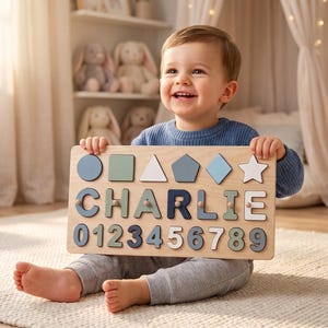 May include: A rectangular wooden puzzle board featuring various geometric shapes, the name CHARLIE in large block letters, and the numbers 0 through 9. The puzzle pieces are painted in shades of blue, green, white, and grey.