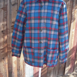 May include: A blue, red, and gray plaid flannel shirt with a button-up front and two pockets.
