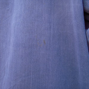 May include: Close-up of a blue denim fabric with a subtle texture. The fabric has a slight sheen and appears to be soft and comfortable.