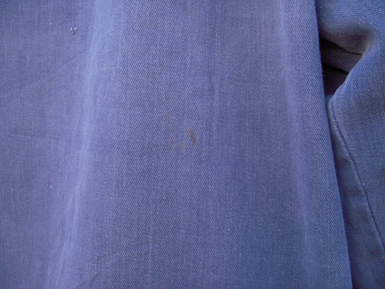 May include: Close-up of a blue denim fabric with a subtle texture. The fabric has a slight sheen and appears to be soft and comfortable.