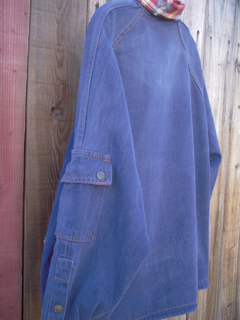 May include: A blue denim shirt with a single button on the left cuff and a patch pocket on the right sleeve.