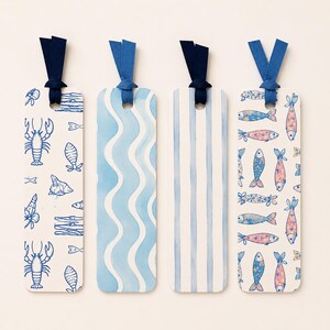 May include: Four rectangular bookmarks with rounded corners and fabric ribbons. The first features blue line drawings of lobsters and shells. The second has light blue wavy lines. The third has vertical blue stripes. The fourth shows patterned fish.