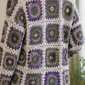 May include: A long-sleeved cardigan constructed from joined square crochet motifs. The pattern features a repeating design of concentric circles in shades of purple, light green, and dark green, all outlined with a white yarn border.