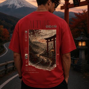 May include: Red t-shirt with a Japanese landscape graphic on the back, featuring a road winding towards a traditional gate and mountain. The shirt has the word "ALTURE" and Japanese text. The person is wearing black trousers and sunglasses.