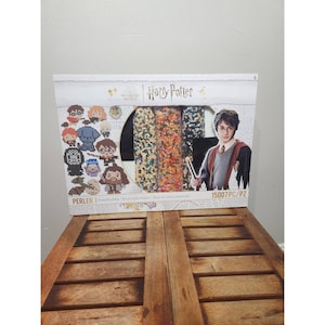Könnte beinhalten: Ein Harry Potter Perler Bügelperlen-Set in einer rechteckigen Schachtel mit einer Grafik von Harry Potter und verschiedenen verpixelten Charakterdesigns. Die Verpackung zeigt das Wizarding World Logo, den Markennamen Perler und 15007 Teile.