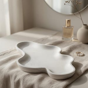 May include: A white, cloud-shaped decorative tray with a smooth, matte finish and subtle grey marbling throughout. The tray features a shallow, organic, multi-lobed basin with raised edges, designed for holding small items on a flat surface.