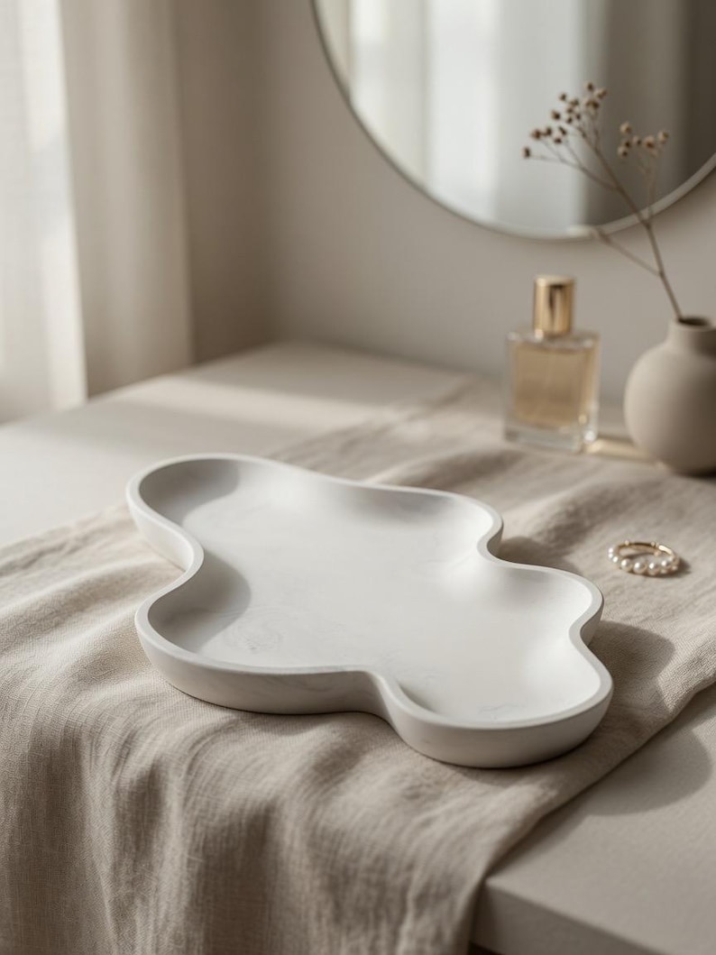 May include: A white, cloud-shaped decorative tray with a smooth, matte finish and subtle grey marbling throughout. The tray features a shallow, organic, multi-lobed basin with raised edges, designed for holding small items on a flat surface.