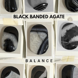 May include: A collection of oval-shaped black banded agate stones displayed on individual cards. Each stone features unique patterns of deep black and translucent white crystalline structures. The text BLACK BANDED AGATE and BALANCE is visible.