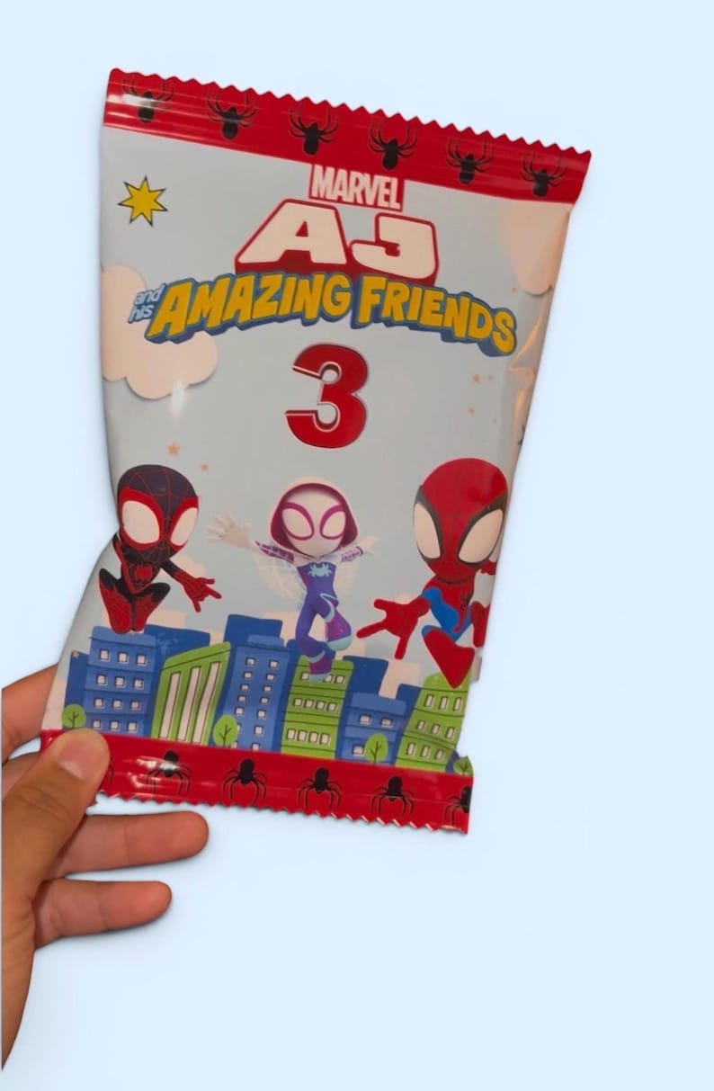 May include: A Marvel "Amazing Friends" snack bag featuring Spider-Man characters. The bag has a red top with spider graphics and the text "Marvel". The bag has a light blue background with the number "3" in red.