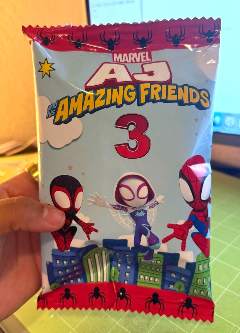 May include: A sealed package featuring Marvel's "Amazing Friends" characters. The package has a light blue background with illustrations of Spider-Man, Miles Morales, and Spider-Gwen. The number "3" is prominently displayed.