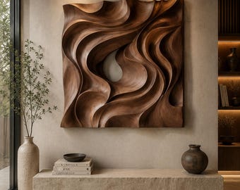 May include: A large square wall art piece made of dark brown wood featuring deep, flowing, wave-like carved textures. The sculpture has a central hollow opening and is mounted on a light beige wall above a long, rectangular stone bench.