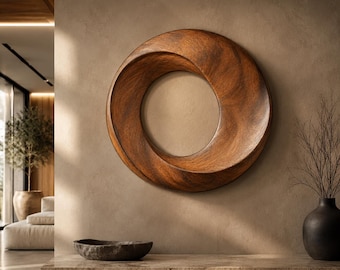 May include: A circular wall sculpture crafted from dark brown wood with a smooth, polished finish. The piece features a continuous, twisted, ring-like form with a hollow center, showcasing natural wood grain patterns throughout its curved surface.