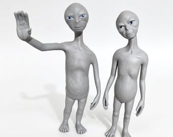 May include: Two grey extraterrestrial figurines with smooth skin, large oval heads, and bright blue eyes. One figure stands with its right arm raised in a greeting gesture, while the other stands beside it with arms resting at its sides.