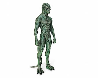 May include: A standing humanoid figurine with green, textured, reptilian skin. The creature features a slender, muscular build, a pointed head with large dark eyes, and a long tail extending from the back. It has three-toed feet with dark claws.