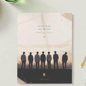 May include: A notebook with a landscape design featuring seven silhouetted figures standing on a horizon line against a sunset backdrop. The text "seven souls one dream endless love" is printed above the figures. The bottom of the notebook has a logo and Korean text.