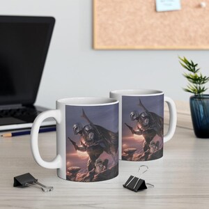 May include: Two white ceramic mugs featuring a printed illustration of a silver-armored warrior in a cape holding a blaster, standing on a rocky landscape with a glowing planet in the background, accompanied by a small creature in a robe.