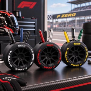 May include: Three black circular pen holders shaped like racing tires, each featuring the Pirelli logo and P Zero text in white, red, and yellow. Each tire has a central black wheel rim and holds three pens of various colors and metallic finishes.
