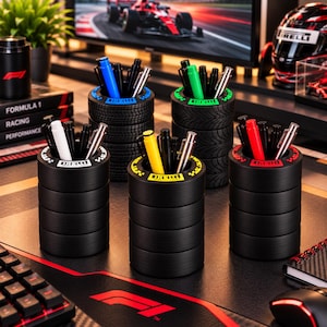 May include: Five cylindrical pen holders designed to resemble stacked racing tires. Each holder features a colored rim with the Pirelli logo and contains various pens. The set includes black, blue, green, yellow, white, and red accents.