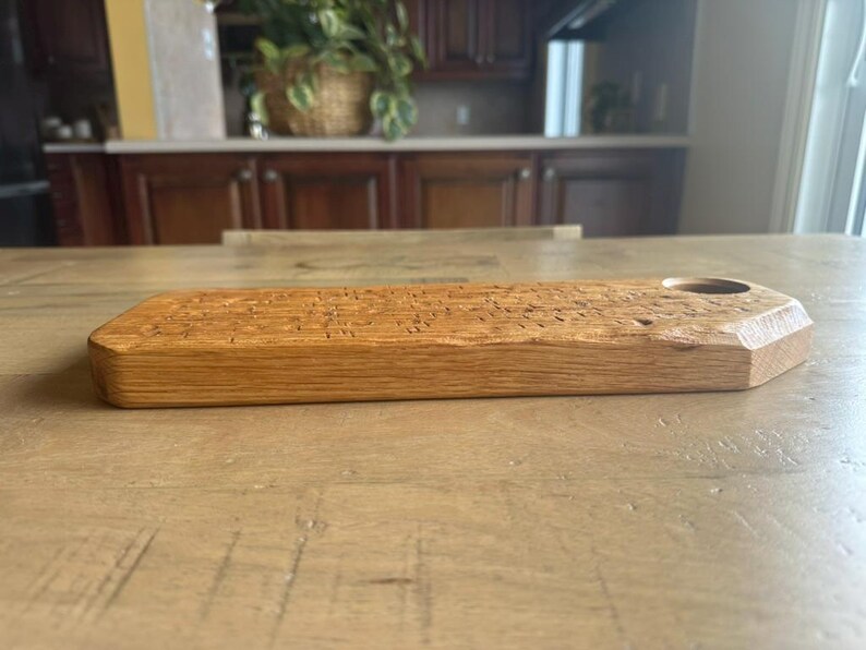 May include: A rectangular wooden serving board with a natural light brown grain and a smooth finish. The board features a single circular cutout near one end, with beveled edges along the corners, showcasing the organic texture of the wood.