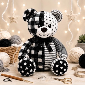 Peut inclure: Un ours en peluche crocheté à la main présentant un motif noir et blanc avec des mélanges de carreaux, de rayures, d'étoiles et de cœurs. L'ours porte un nœud en ruban de satin noir au cou et possède des yeux et un nez en plastique foncé.