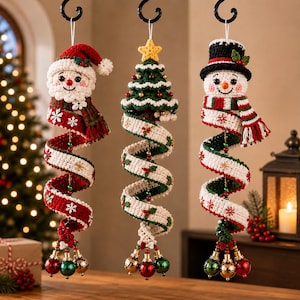 Op de afbeelding: Drie hangende gehaakte ornamenten met een kerstman, een kerstboom en een sneeuwpop. Elke figuur heeft een lange, spiraalvormige staart in rood, wit en groen met sneeuwvlok- of hulstpatronen, afgewerkt met kleine metalen belletjes aan de onderkant.