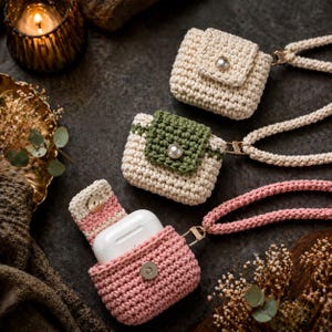 May include: Three crochet earbud cases with matching straps. One is solid cream, one is cream with a green flap, and one is pink, shown open with a white earbud charging case inside. Each features a gold-tone metal snap button closure.