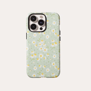 May include: A smartphone case featuring a light sage green background with a repeating pattern of white daisies with yellow centers. The case has a black camera cutout frame at the top left corner, exposing the three lenses of the smartphone.