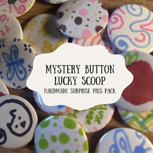 Può includere: Una collezione di spille rotonde fatte a mano con vari disegni e colori. Alcune spille presentano motivi astratti, mentre altre hanno illustrazioni floreali o stravaganti. Il testo "MYSTERY BUTTON LUCKY SCOOP HANDMADE SURPRISE PINS PACK" è visualizzato.