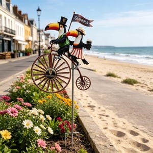 Peut inclure: Un piquet de jardin en métal fantaisiste représentant deux toucans sur un grand-bi. L'un porte un chapeau haut de forme, l'autre un chapeau et une jupe rayée, tenant une Guinness. Le vélo a un logo Guinness et une bannière.